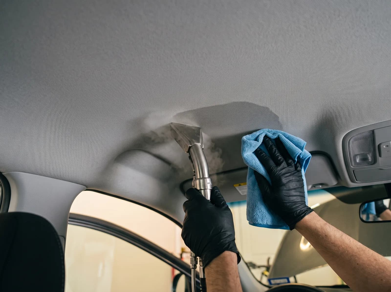 Steam cleaning nozzle and catch towel working across a car headliner